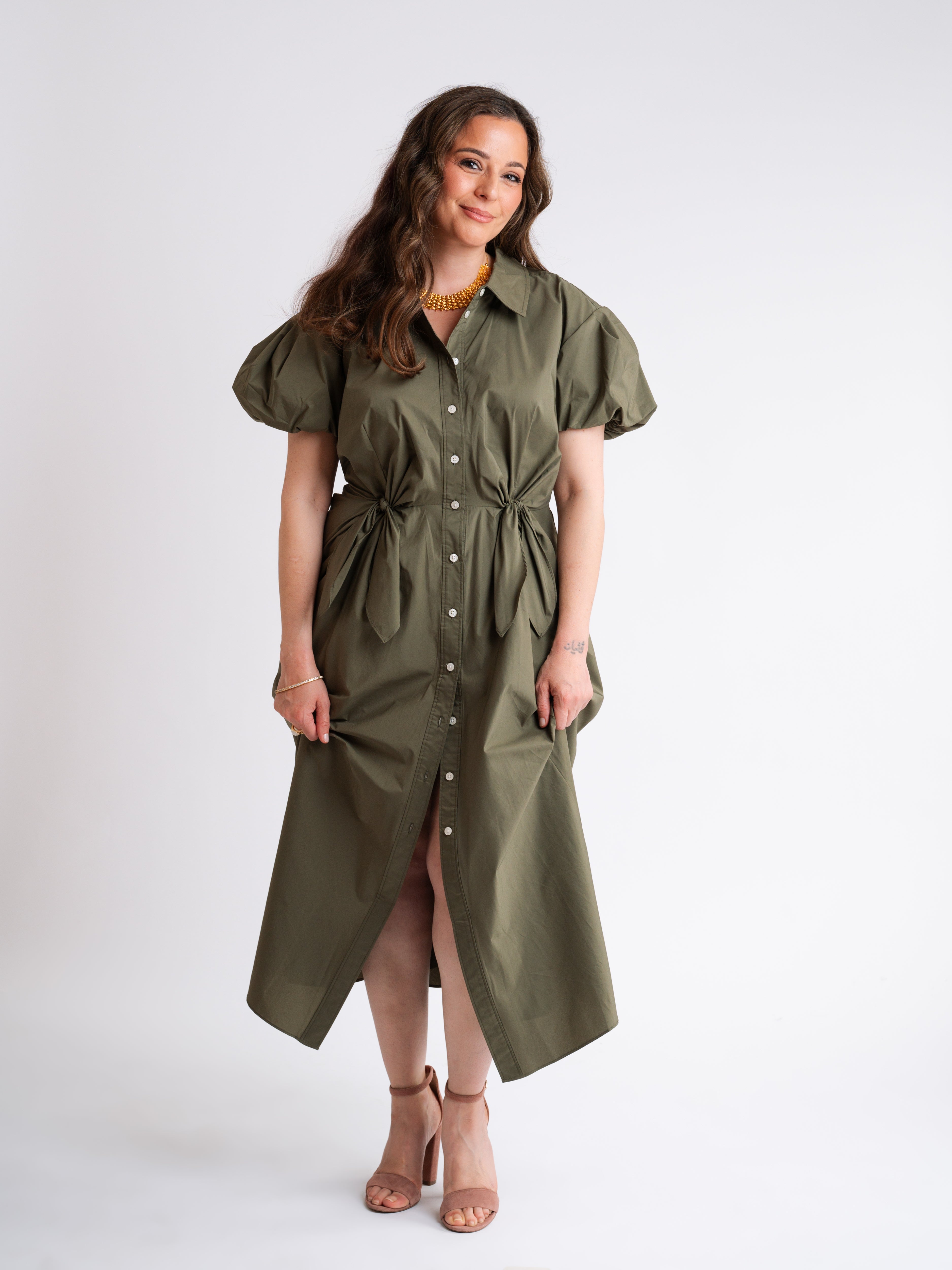 Vivian smiling wearing a green dress with a white background