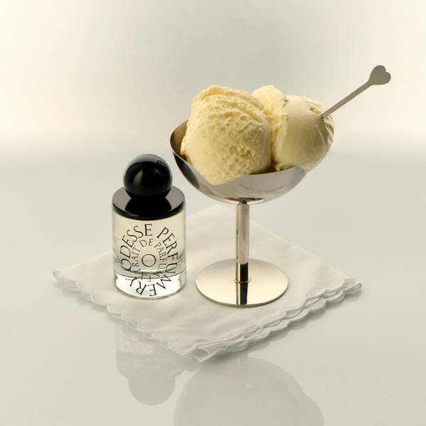 Bottle of Odesse Perfume with a small bowl of vanilla ice cream on a reflective surface.