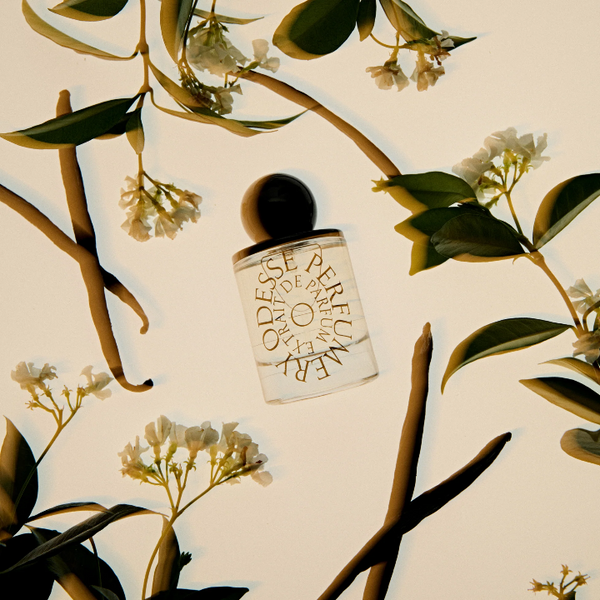 Perfume bottle surrounded by floral and leaf patterns on a beige background