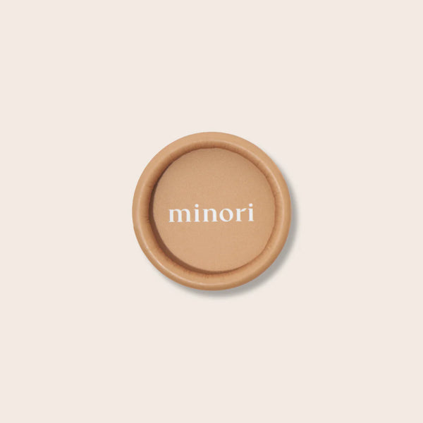 Round brown compact with 'minori' branding on a beige background