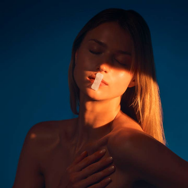 Woman with tape over her mouth against a blue background