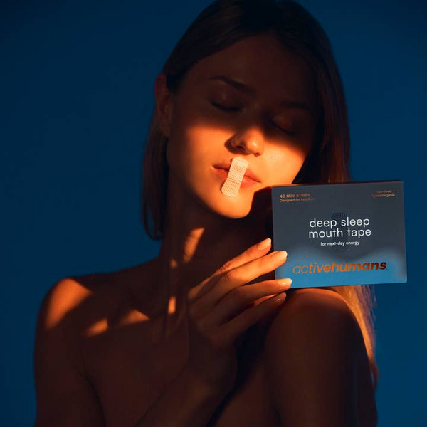 Woman wearing deep sleep mouth tape with a box of 'active humans' mouth tape against a blue background