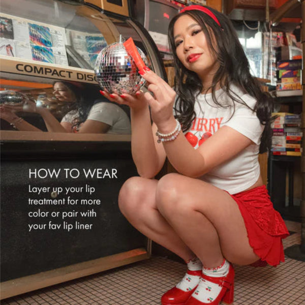 Woman in a red skirt and white top holding a disco ball in a vintage store setting.