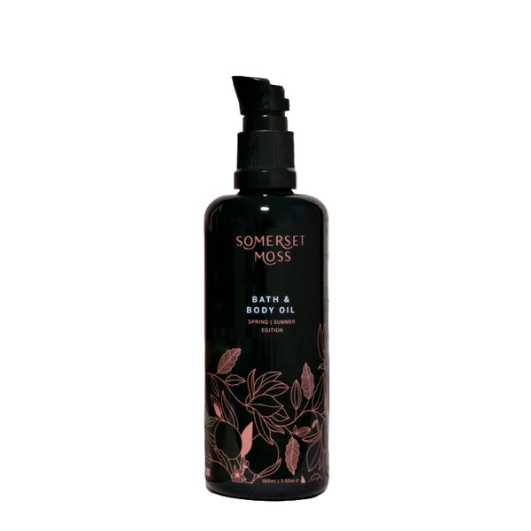 Bottle of Somerset Moss bath and body oil on a light pink background