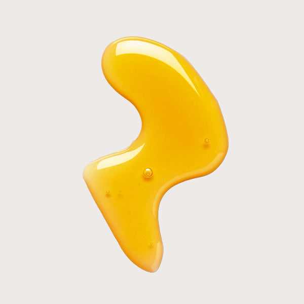 Yellow body oil on a light gray background