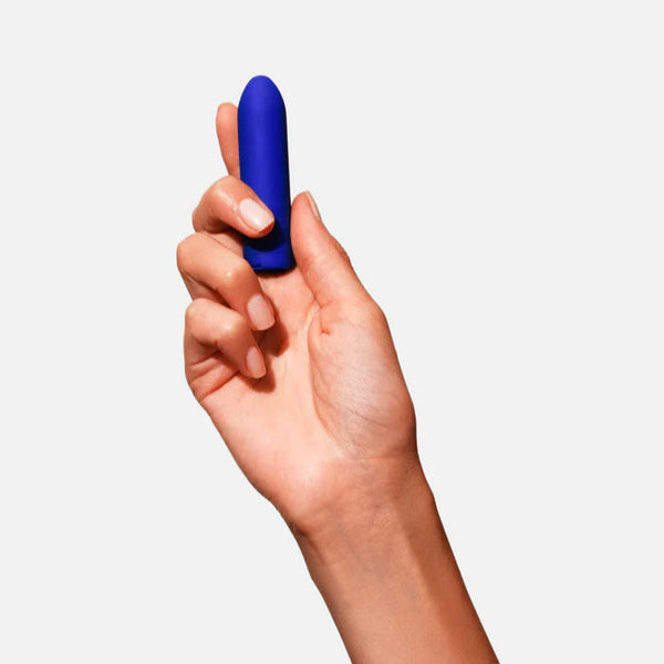 Hand holding a cobalt blue Zee Bullet Vibrator against a white background