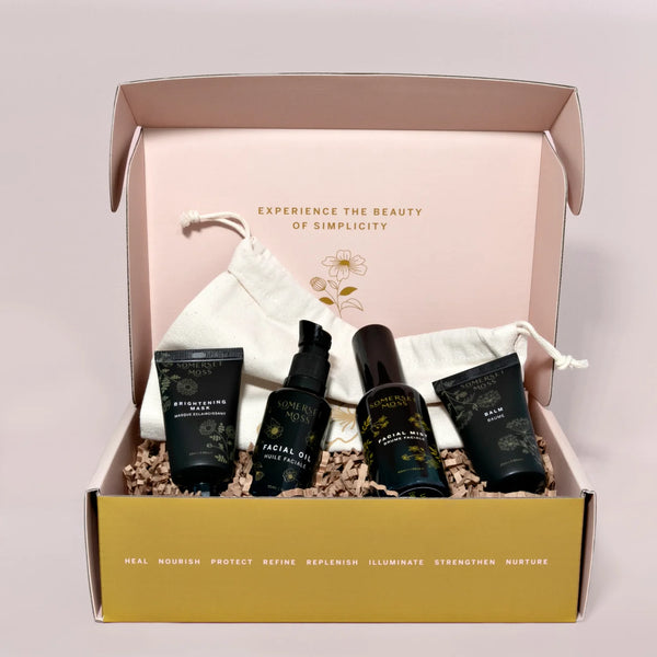 Skincare product set in a box with a drawstring bag on a light pink background