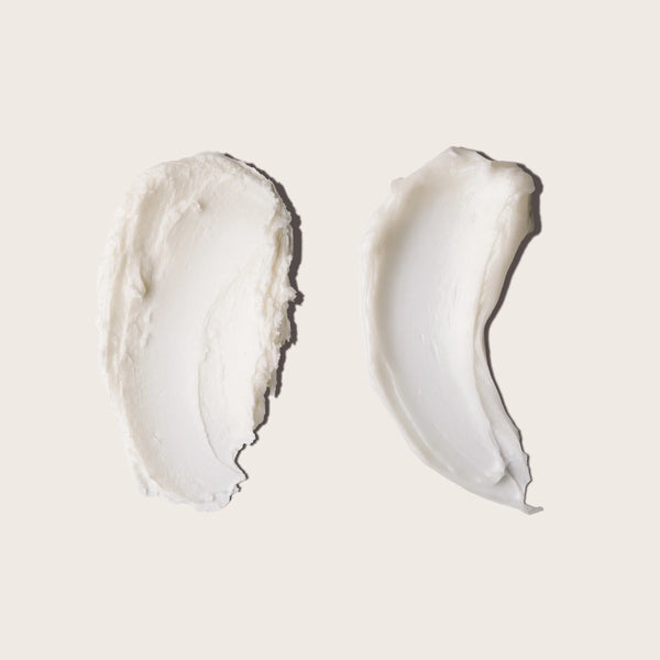 Two swatches of white cream (Everists shampoo and deep conditioning concentrates) on a light beige background