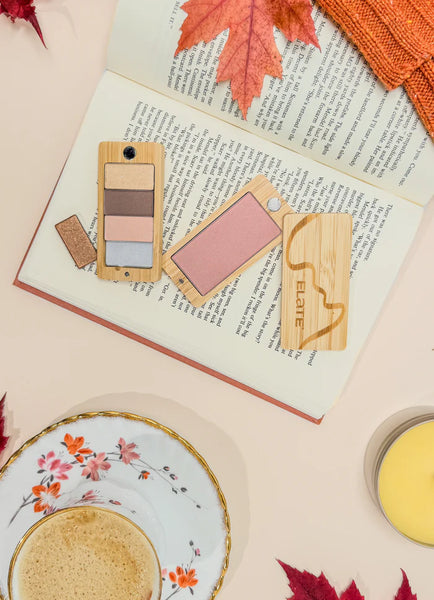 Makeup products on an open book with autumn leaves and a teacup in the background