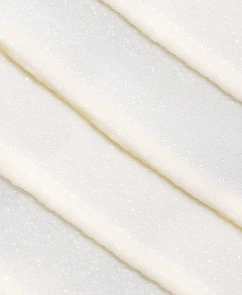 Close-up of a white swatch of Golden Glow Eye Balm with a subtle pattern on a light gray background