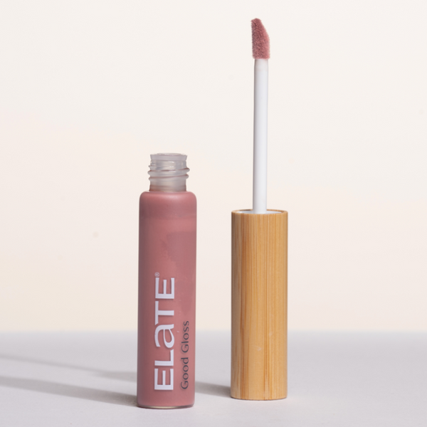 Lip gloss with wooden applicator in pink shade named Good Gloss Aurora on a light background