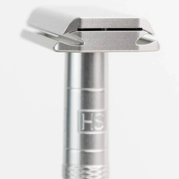 Close-up of a silver safety razor on a white background