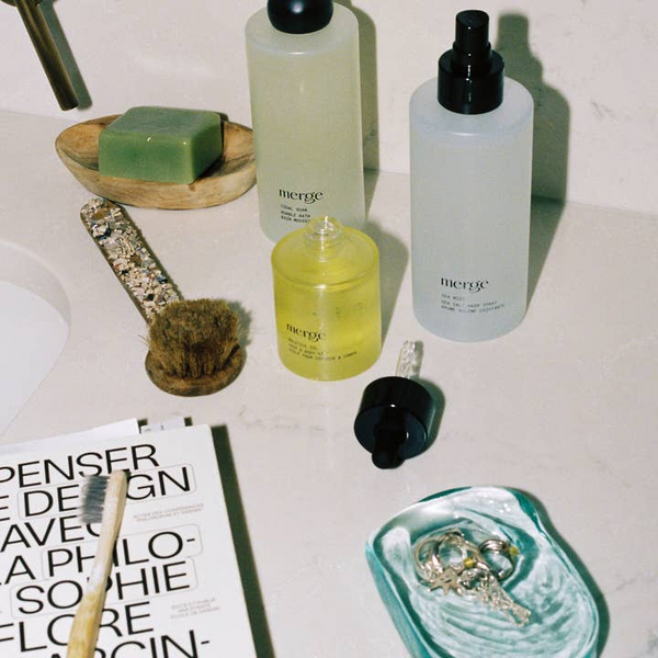 Bathroom counter with 'merge' skincare products and a magazine.