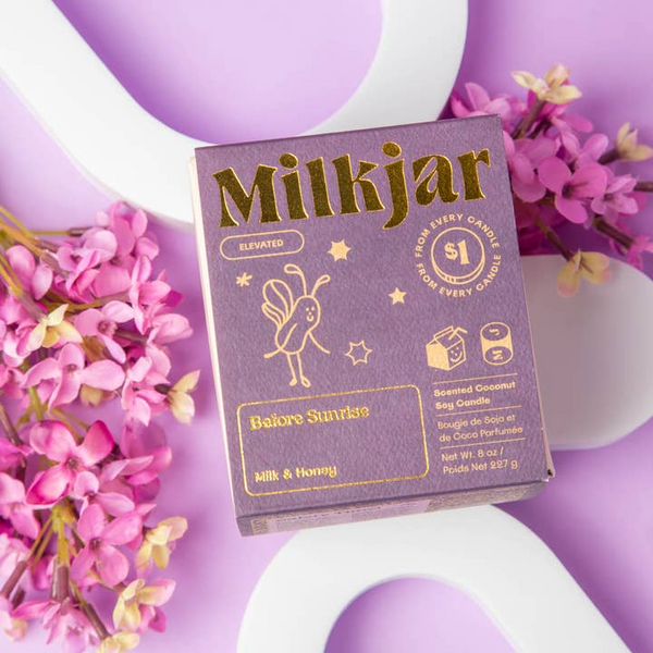 Milkjar candle packaging with gold text on a purple background with flowers