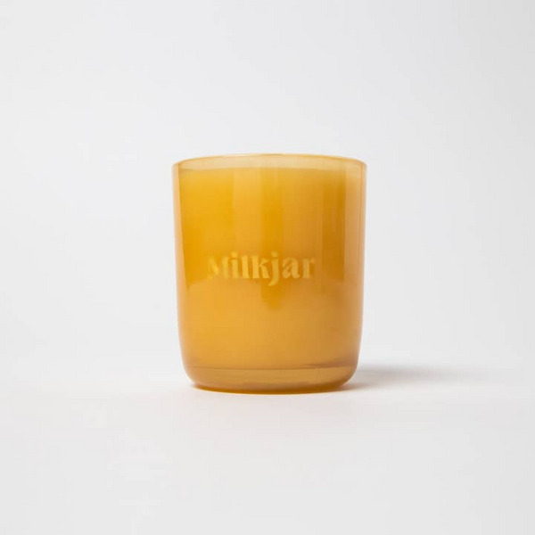 Yellow candle with 'Milkjar' branding on a white background