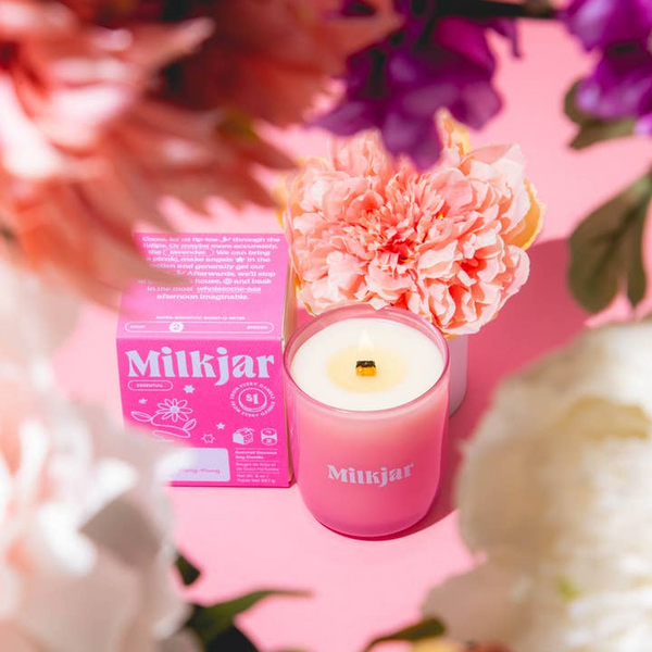Pink Milkjar candle and packaging with flowers on a pink background