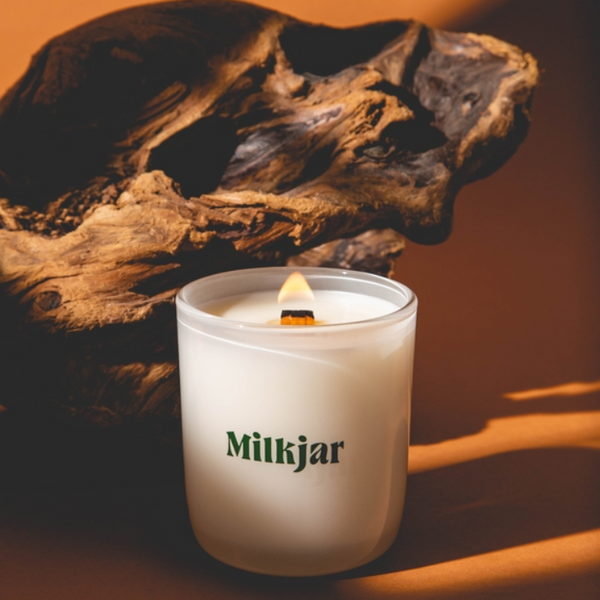 Milkjar candle with a wooden log in the background
