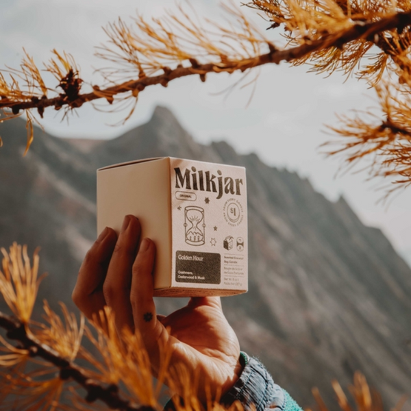 Hand holding a 'Miljkjar' product box against a mountainous background