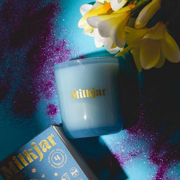 Blue candle with 'Milkjar' branding on a colorful background
