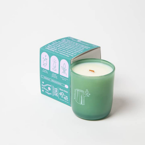 Green candle with a matching box on a white background