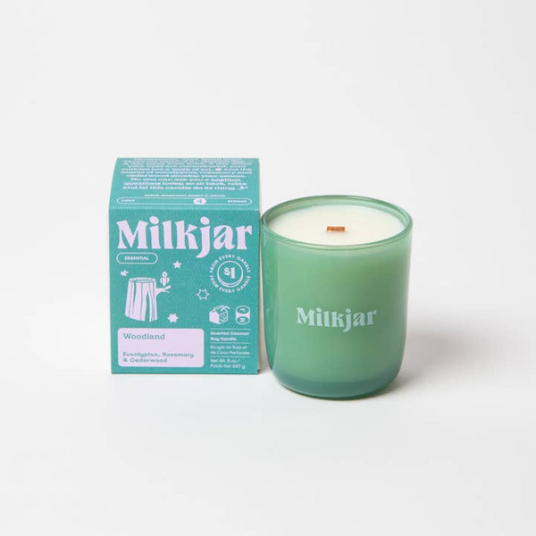 Green candle with 'Milkjar' branding next to its packaging on a white background