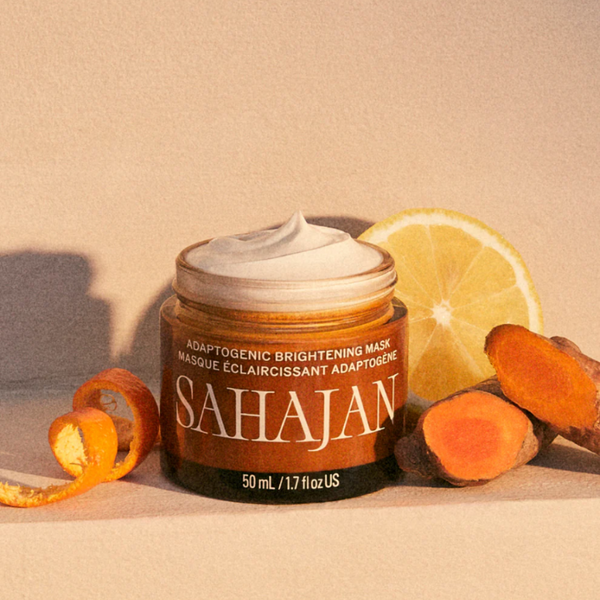 Sahajan adaptogenic brightening mask jar with turmeric root and lemon on a beige background