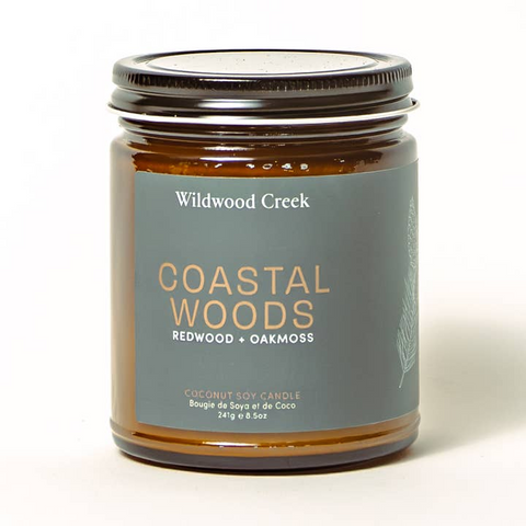 Candle jar labeled 'Coastal Woods' by Wildwood Creek on a white background