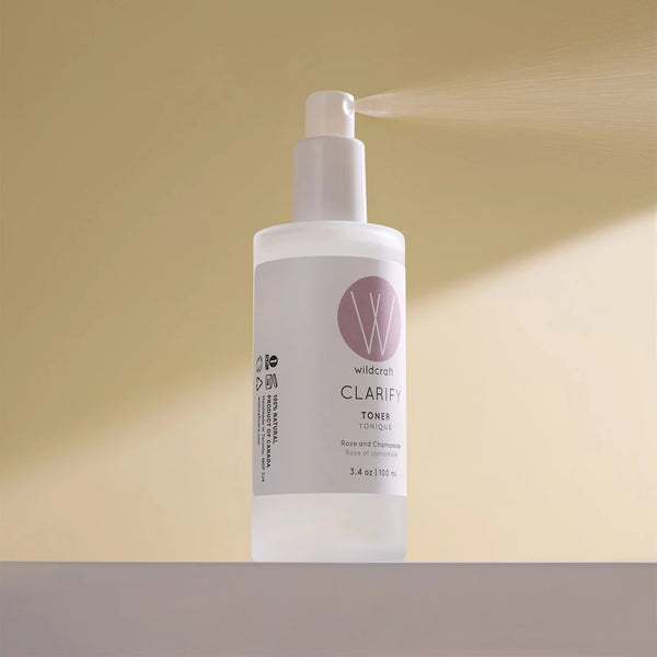 Wild Dast Clarify Toner spray bottle on a neutral beige background, with the pump spraying a fine mist.