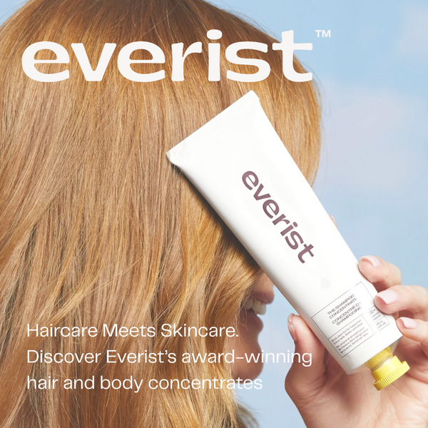Person holding a tube of Everist shampoo concentrate with a light blue background