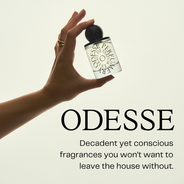 Hand holding a Odesse perfume bottle with text about fragrances on a light background